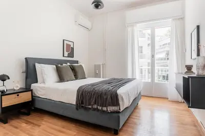 a bedroom with a bed and a large window at Acropolis Sunlight 2BR Apartment by UPSTREET in Athens