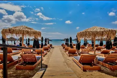 a row of chairs and umbrellas on a beach at Varkiza Seaside 2BD Apartment in Varkiza