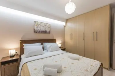 a bedroom with a large bed with wooden cabinets at Varkiza Seaside 2BD Apartment in Varkiza