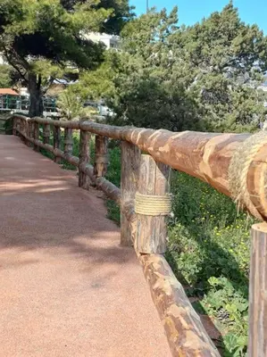 a wooden fence next to a road with trees at Varkiza Seaside 2BD Apartment in Varkiza
