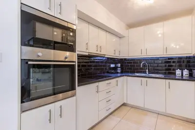 a kitchen with white cabinets and black appliances at Varkiza Seaside 2BD Apartment in Varkiza