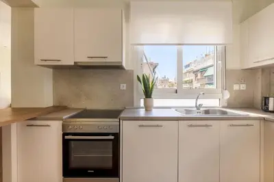 a kitchen with white cabinets and a sink and a window at Koukaki 2BR Apartment by UPSTREET in Athens