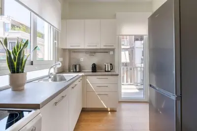 a kitchen with white cabinets and a stainless steel refrigerator at Koukaki 2BR Apartment by UPSTREET in Athens