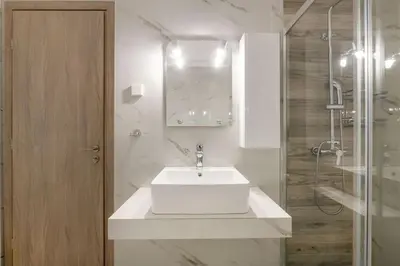 a white bathroom with a sink and a shower at Koukaki 2BR Apartment by UPSTREET in Athens