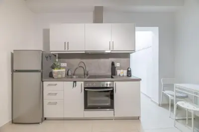 a kitchen with white cabinets and a stainless steel refrigerator at The HostMaster Aethereal Style in Athens
