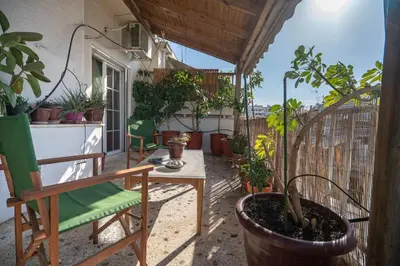 a balcony with a chair and a table and potted plants at N kosmos metro st 1 bedroom 4 pers flat by MPS in Athens