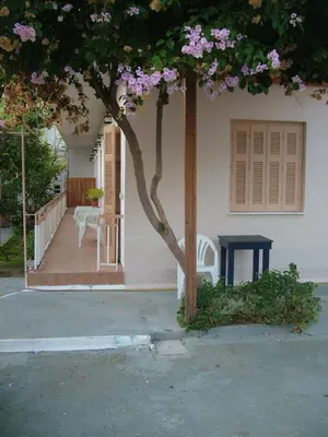 a house with a tree and a blue table at George's Apartment in Agia Marina Aegina