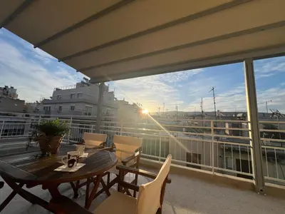 a patio with a table and chairs on a balcony at Cozy apartment with big veranda near Athens centre and metro tram in Athens