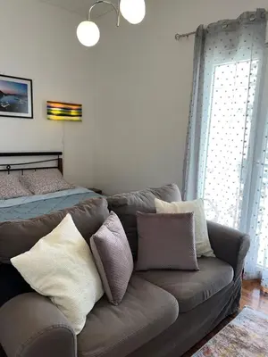 a living room with a couch and a bed at Cozy apartment with big veranda near Athens centre and metro tram in Athens