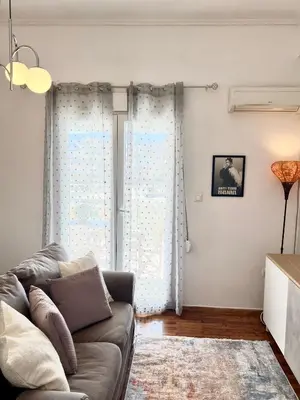 a living room with a couch and a window at Cozy apartment with big veranda near Athens centre and metro tram in Athens