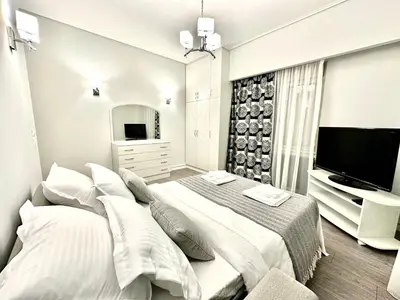 a white bedroom with a large bed and a television at Modern home in Athens