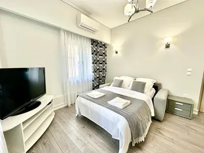 a white bedroom with a bed and a flat screen tv at Modern home in Athens