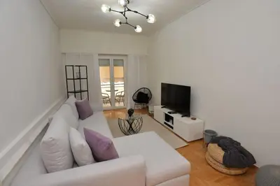 a living room with a white couch and a television at Zen Oasis Apartment in Athens