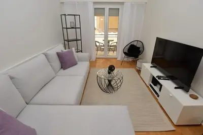 a living room with a white couch and a television at Zen Oasis Apartment in Athens