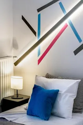 a bed with a blue pillow and a wall with arrows at Athenian Oasis Near Athens Metro Mall in Athens