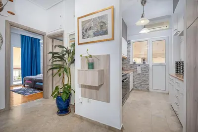 a kitchen with white walls and a plant in a blue vase at Athenian Oasis Near Athens Metro Mall in Athens