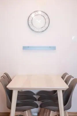 a table with chairs and a clock on a wall at Spacious Urban Apt in the Heart of Athens in Athens