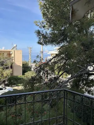 a fence in front of a tree and buildings at Sunny Modern Beach Retreat Steps from the Shore in Saronida
