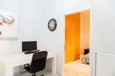 a desk with a computer and a clock on a wall at Private Spacious Apartment in Athens