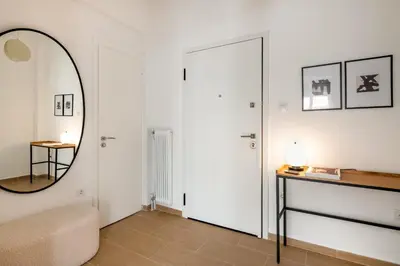 a white living room with a mirror and a table at Sunny 2BR Apartment in Nea Smyrni by UPSTREET in Athens