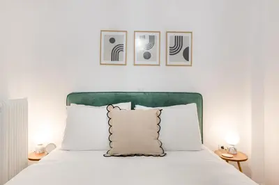 a bed with a green headboard and white pillows at Sunny 2BR Apartment in Nea Smyrni by UPSTREET in Athens