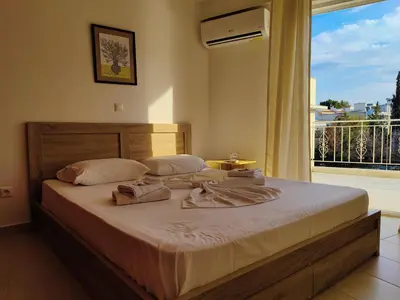 a bed in a bedroom with a large window at Finikas Spata Holiday Apartment in Spáta