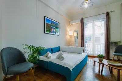 a living room with a blue couch and two chairs at Olive House close to Acropolis in Athens