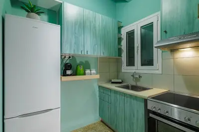 a kitchen with green cabinets and a white refrigerator at Olive House close to Acropolis in Athens