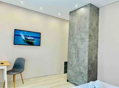 a room with a chair and a tv on a wall at Port Twins Suites No2 in Piraeus