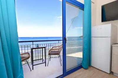 a kitchen with a balcony with a view of the ocean at Niko's Beach Suites No1 in Agia Marina Aegina