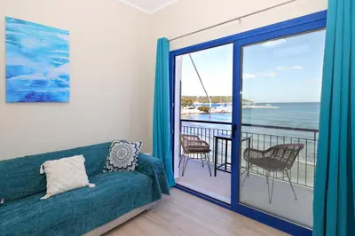 a living room with a couch and a balcony at Niko's Beach Suites No1 in Agia Marina Aegina