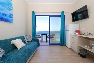 a living room with a blue couch and a balcony at Niko's Beach Suites No1 in Agia Marina Aegina