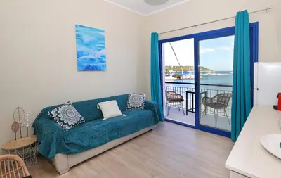 a living room with a couch and a balcony at Niko's Beach Suites No1 in Agia Marina Aegina