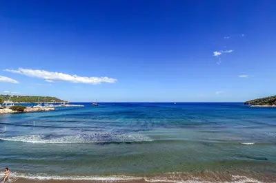 a person walking on the beach near the water at Niko's Beach Suites No1 in Agia Marina Aegina