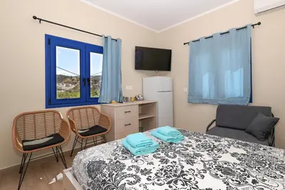 a bedroom with a bed and two chairs and a window at Niko's Beach Suites Νο2 in Agia Marina Aegina