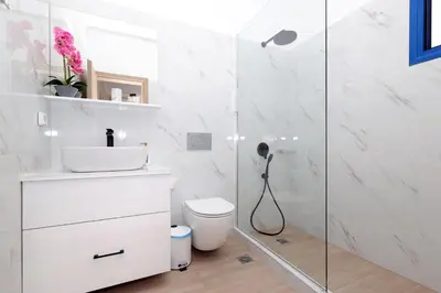 a bathroom with a toilet and a glass shower at Niko's Beach Suites Νο2 in Agia Marina Aegina