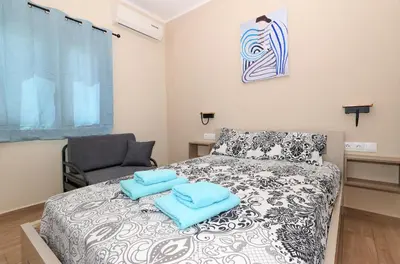 a bedroom with a bed with blue towels on it at Niko's Beach Suites Νο2 in Agia Marina Aegina