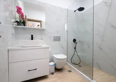 a white bathroom with a shower and a toilet at Niko's Beach Suites Νο2 in Agia Marina Aegina