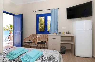 a room with a bed and a desk with a television at Niko's Beach Suites Νο2 in Agia Marina Aegina