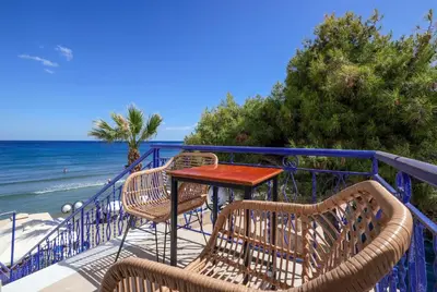 a table and chairs on a balcony overlooking the beach at Niko's Beach Suites Νο2 in Agia Marina Aegina