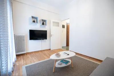 a white living room with a table and a tv at kato patisia cozy apartment for 2 persons by MPS in Athens