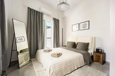 a white bedroom with a bed and a mirror at City Center Suite in Athens