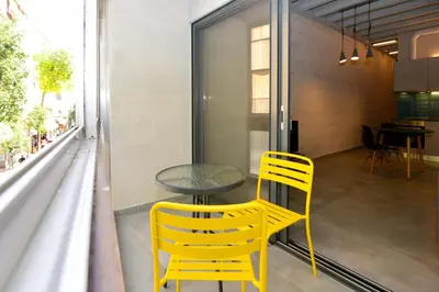 a table and two yellow chairs on a balcony at Athens industrial design apt 5 min from Metro in Athens