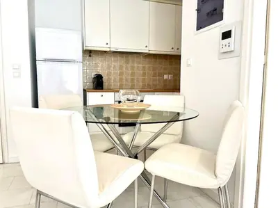a kitchen with a glass table and white chairs at Pratinou 1B/R apartment in Athens