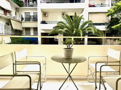 a table and chairs on a balcony with a plant at Pratinou 1B/R apartment in Athens