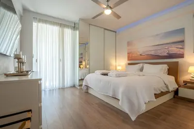 a bedroom with a large white bed with a painting on the wall at Athens Riviera Aelia Luxury Suite By The Sea in Athens