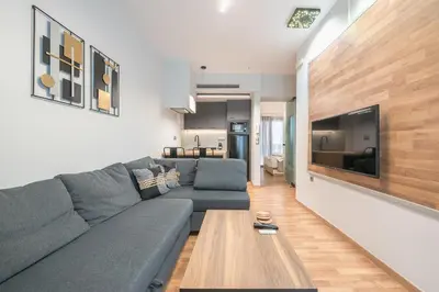 a living room with a gray couch and a table at Newly Renovated Loft 1 min walk from metro by Cloudkeys in Athens