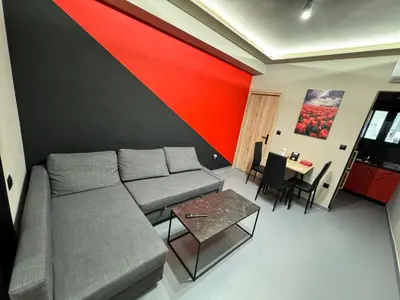 a living room with a couch and a red wall at Samurai apartments -Catrin- in Koropíon
