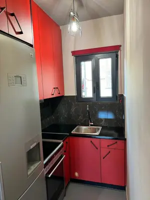 a red kitchen with a sink and a window at Samurai apartments -Catrin- in Koropíon