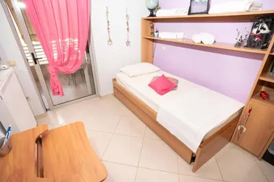 a small bedroom with a bed and a window at Maria's Airport Apartment, 4' metro, 10' airport, 15' beach, 40' city center in Koropíon